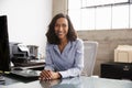 Young mixed race woman at office desk smiling to camera Royalty Free Stock Photo