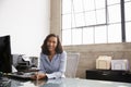 Young mixed race woman at office desk smiling to camera Royalty Free Stock Photo