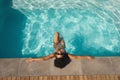 Young mixed-race woman with sunglasses leaning on edge of pool Royalty Free Stock Photo