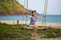 Asian woman swinging on a wooden swing at a seaside tropical beach. Royalty Free Stock Photo