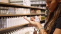 Young Mixed Race Woman Testing Ethical Skin Care Cream on Her Hand at Cosmetics Corner in Supermarket. 4K.