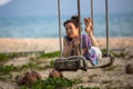 Young mixed race woman on the wooden swings on sea beach. Royalty Free Stock Photo