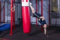 Athlete MMA fighter inflicts powerful kick on punching bag with support on his arm.
