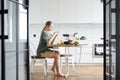 Young mobile female with smartphone texting by served table