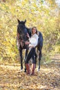 Young equestrian woman walking horse in autumn park Royalty Free Stock Photo