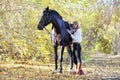 Young equestrian woman walking horse in autumn park Royalty Free Stock Photo