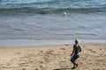 Young model playing sand football on the beach under strong summer sun