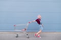 Young model poses with a cart on the background of a blue wall Royalty Free Stock Photo