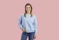 Happy smiling young girl in sweatshirt and jeans posing isolated on pink background Royalty Free Stock Photo