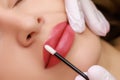 young model With a slight smile, on which permanent lip makeup is done with red pigment for tattooing