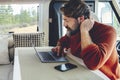 Young modern adult man work on laptop computer in remote working and digital job lifestyle inside a modern and connected camper Royalty Free Stock Photo