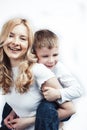 Young modern blond curly mother with cute son together happy smiling family posing cheerful on white background Royalty Free Stock Photo