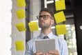 Young modern business man using adhesive notes while standing behind the glass wall in the office Royalty Free Stock Photo
