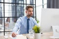 Young modern business man working using computer with collegues on the background while sitting in the office. Royalty Free Stock Photo