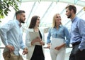 Young modern colleagues in smart casual wear having a brainstorm meeting while standing in the creative office.