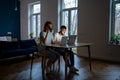 Young modern freelancing couple sitting at table in living room working from home together Royalty Free Stock Photo