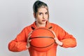 Young modern girl holding basketball ball skeptic and nervous, frowning upset because of problem