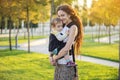 Young modern happy mom with baby son walking in Sunny Park. The concept of the joy of motherhood Royalty Free Stock Photo