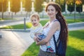 Young modern happy mom with baby son walking in Sunny Park. Concept of the joy of motherhood and autumn mood Royalty Free Stock Photo