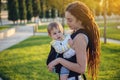 Modern happy mother with baby son in ergo backpack walking in Sunny summer day. Concept of the joy of motherhood Royalty Free Stock Photo