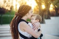 Young happy mother with baby son in ergo backpack walking in Sunny summer day. Concept of the joy of motherhood Royalty Free Stock Photo