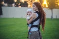 Young modern happy mother with baby son in ergo backpack walking in Sunny summer day. Joy of motherhood Royalty Free Stock Photo