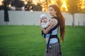 Young modern happy mother with baby son in ergo backpack walking in Sunny summer day. Joy of motherhood Royalty Free Stock Photo