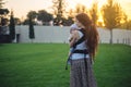 Young modern happy mother with baby son in ergo backpack walking in Sunny summer day. Joy of motherhood Royalty Free Stock Photo