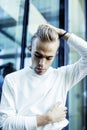 Young modern hipster guy at new building university blond fashion hairstyle having fun, lifestyle people concept Royalty Free Stock Photo