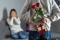 Mans hands hiding holding chic bouquet of red roses and gift with white ribbon behind back and woman with hands over her face awai Royalty Free Stock Photo