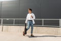 Young modern man model in a white vintage shirt in blue stylish jeans in sunglasses with a black bag walks on the street Royalty Free Stock Photo