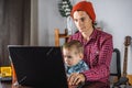 Modern man is working on a laptop, and his little son is sitting on his lap. Concept of family and remote work from home