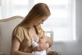 Young mom breastfeed little newborn child at home