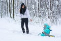 Young mom carries her child on a sled in a winter park Royalty Free Stock Photo