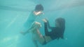 Two asian girls sisters playing together diving underwater in swimming pool.