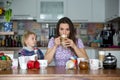 Young mom, drinking many coffees in the morning with her toddler child