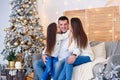 Young mom, father, and their little daughter lovely sitting near Christmas tree on sofa. Royalty Free Stock Photo