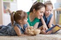 Young mom and her children lying on the floor and reading book Royalty Free Stock Photo