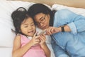 Young mom and her little daughter are using a smartphone on bed Royalty Free Stock Photo