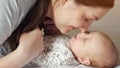 Young mom kisses cheeks and tiny fingers of baby girl Royalty Free Stock Photo