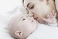 A young mom kisses a newborn baby. Love and tenderness. Close-up. Royalty Free Stock Photo