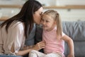 Young mom and little daughter share secrets at home