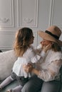 Mom and daughter in white blouses playing in the studio with daffodils. mother`s day