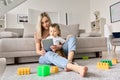 Young mom sitting on floor at home with kid watching movies on tablet. Royalty Free Stock Photo