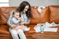 Young mom sitting with newborn son on sofa. Royalty Free Stock Photo