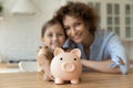 Young mom small daughter show funny piggybank offer bank deposit Royalty Free Stock Photo