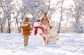 Happy family mother and two little kids making snowman together in winter park outdoors