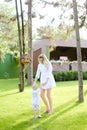 Young mother walking with babe on grass in yard.