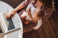 Young mom working remotely on laptop while taking care of her baby. Royalty Free Stock Photo