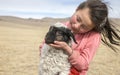 Young mongolian girl carrying a baby sheep in a steppe